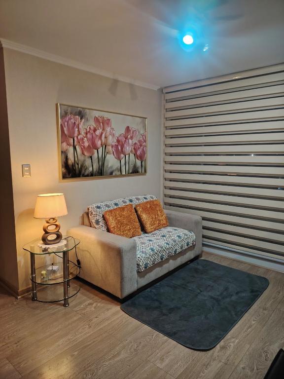 a bedroom with a bed and a table with a lamp at Departamento Los Poetas in Temuco