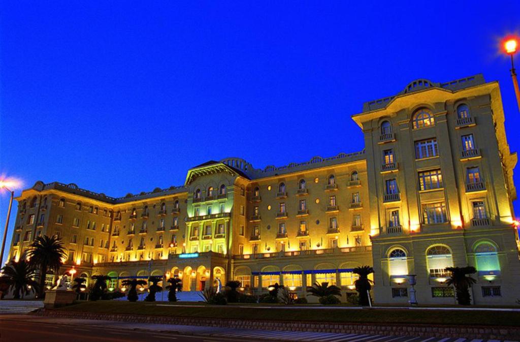 a large building with people standing outside of it at night at Argentino Hotel Casino & Resort in Piriápolis