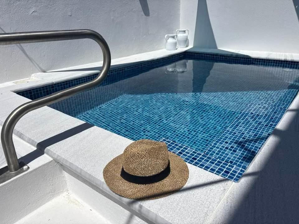 a straw hat sitting on the edge of a swimming pool at OLIA STUDIOS Olga studios in Faliraki