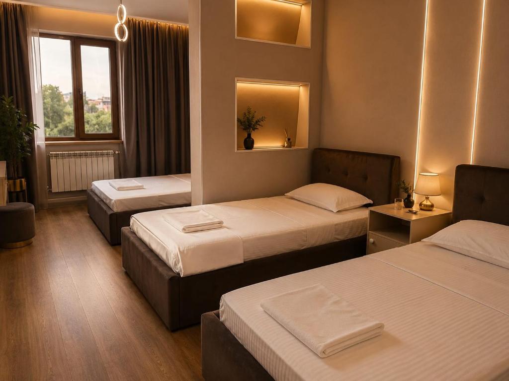 a hotel room with three beds and a window at Grand Sky Hotel in Almaty