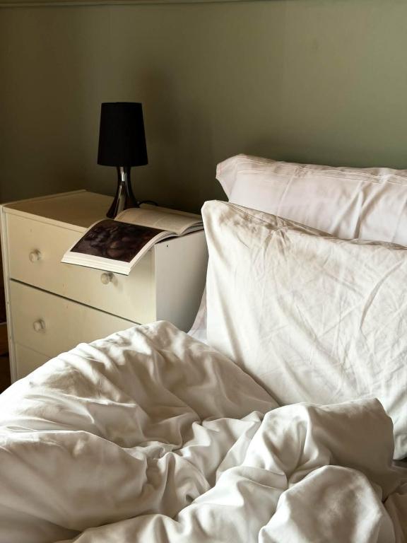 an unmade bed next to a dresser with a lamp at Fjord House Hardanger in Grimo