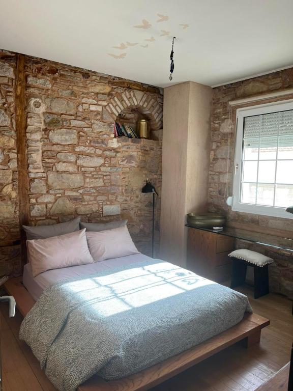 a bed in a room with a brick wall at Homeric poems Suites in Chios
