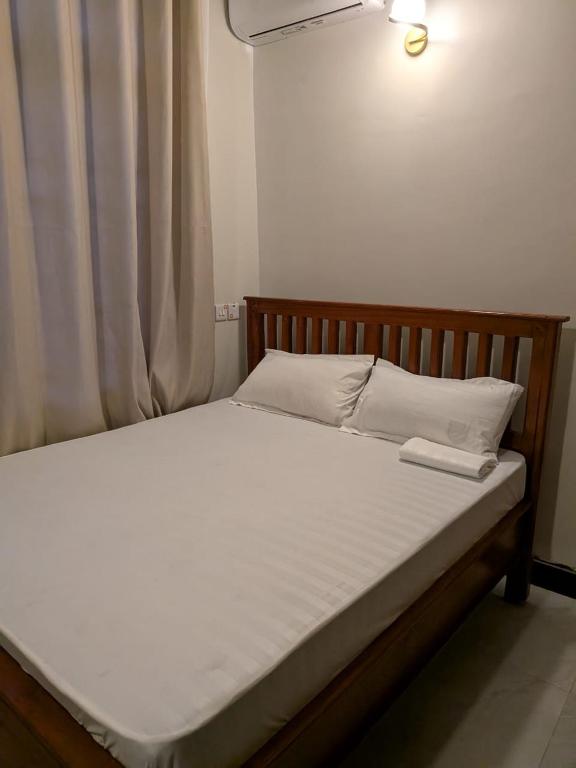 a bed with a wooden frame and white sheets at Nyumbani Executive Lodge in Ilala