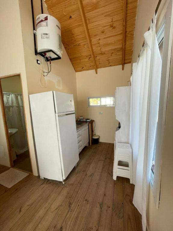 a kitchen with a white refrigerator and a sink at Cabañas Aires de Campo II in Victoria