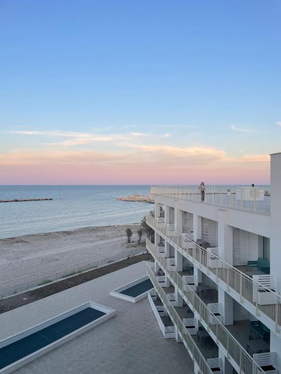 a building on the beach at sunset at Sumus Smart Residence in Porto SantʼElpidio