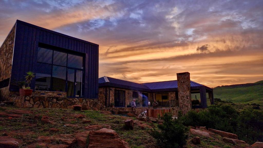 a house on a hill with a sunset in the background at Riverbend on Komati in Machadodorp