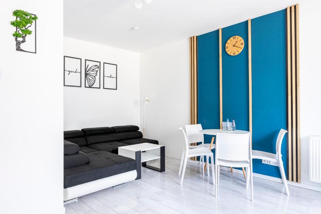 a living room with a couch and a table and a clock at Mechaniczna 5W Premium Apartment with parking in Głogów