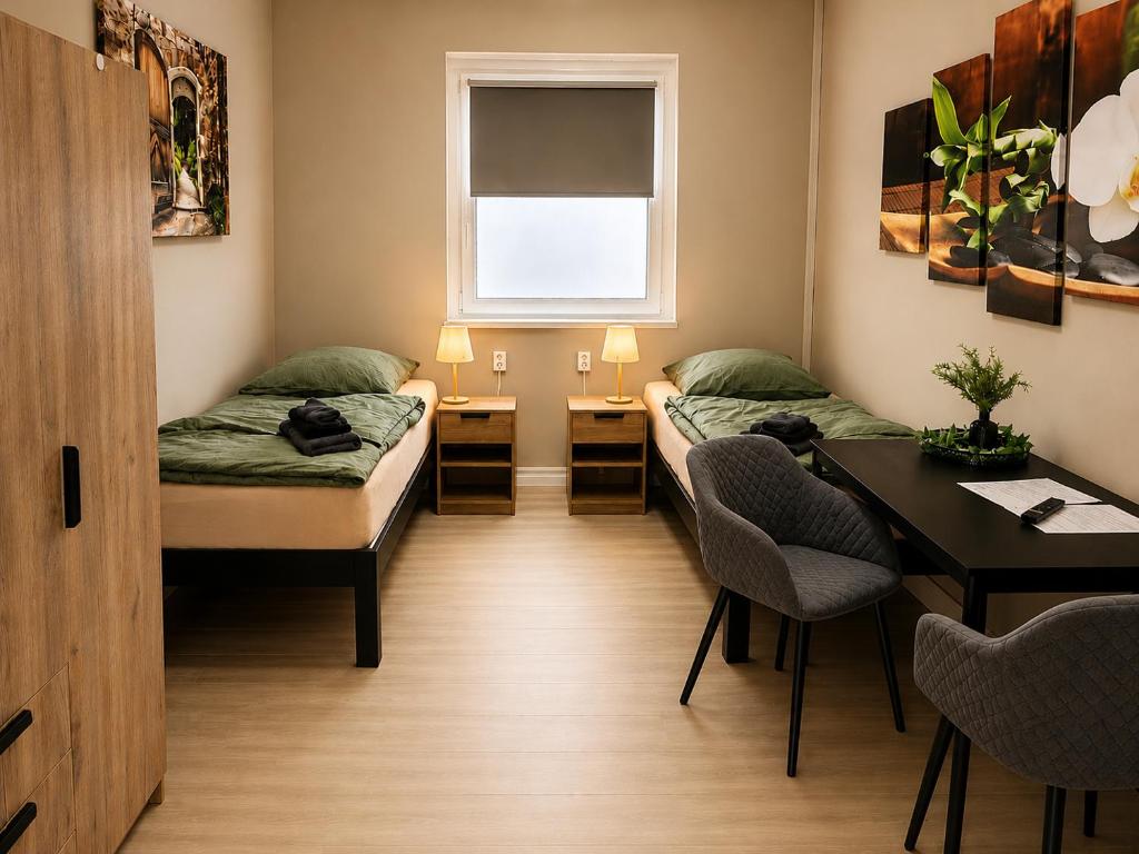 a room with two beds and a table and a window at HK-Vermietung - dezent, ordentlich und preiswert mit allem, was es wirklich braucht in Brieselang