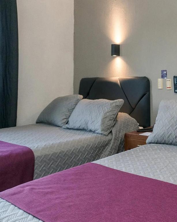 a bedroom with two beds with purple sheets at Hotel Melanie Tepic in Tepic