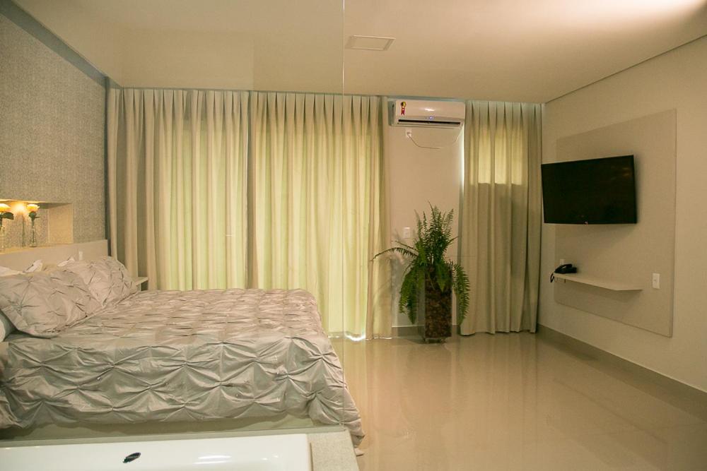 a bedroom with a bed and a flat screen tv at Peçanha Grande Hotel in Peçanha