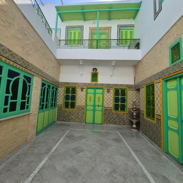 an empty room with green doors and windows at dar Beya in Kairouan