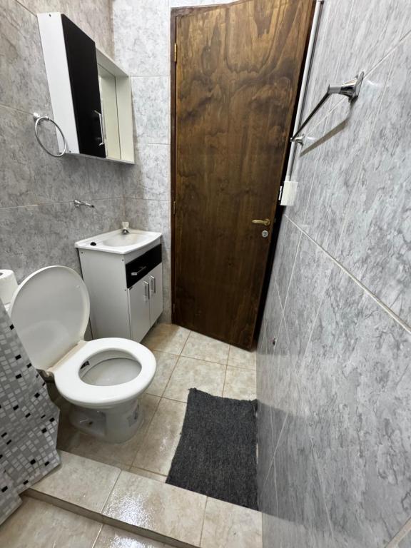 a bathroom with a toilet and a wooden door at Departamento Davis in Eldorado