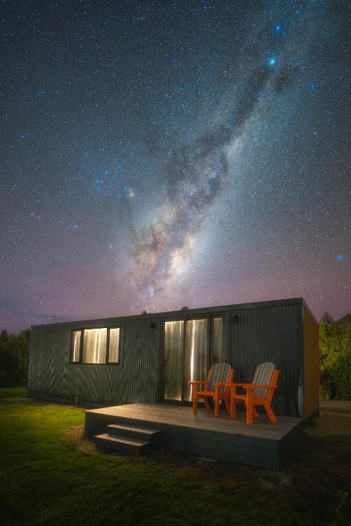 two chairs sitting on a deck under a starry sky at Frogs Hollow in Greytown