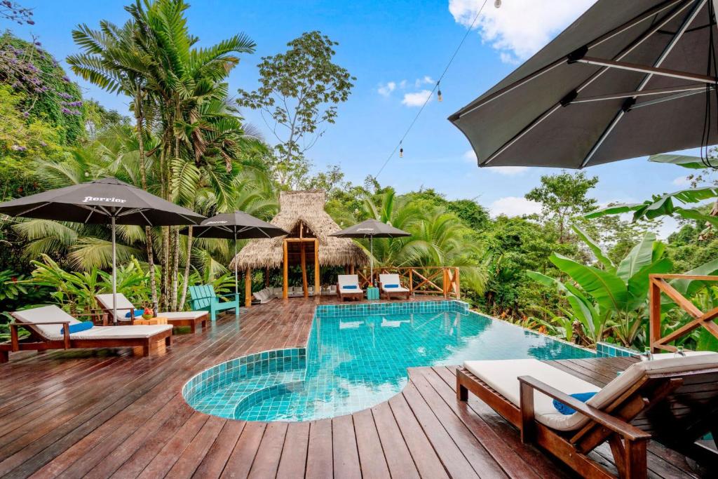 a pool at a resort with chairs and umbrellas at Central Hotel Bocas del Toro in Valle de Agua