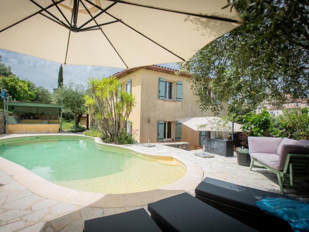 a swimming pool with an umbrella and a house at Belle vue in Flayosc