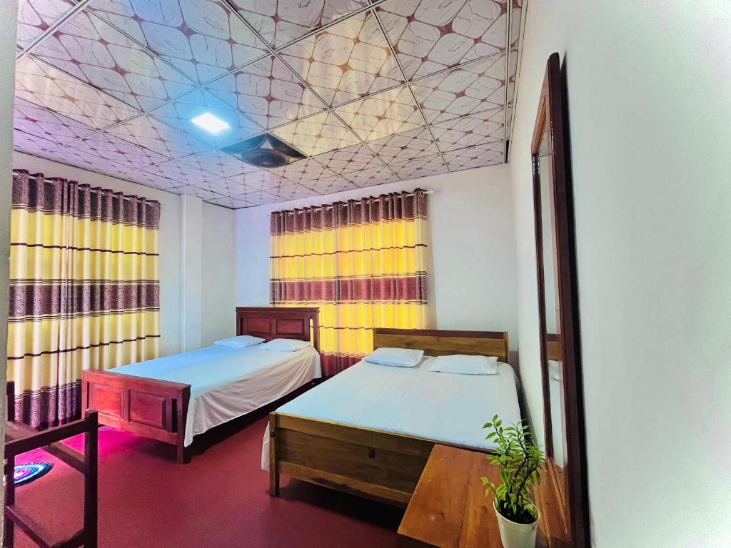 two beds in a room with a mosaic ceiling at River Park Holiday Home in Badulla