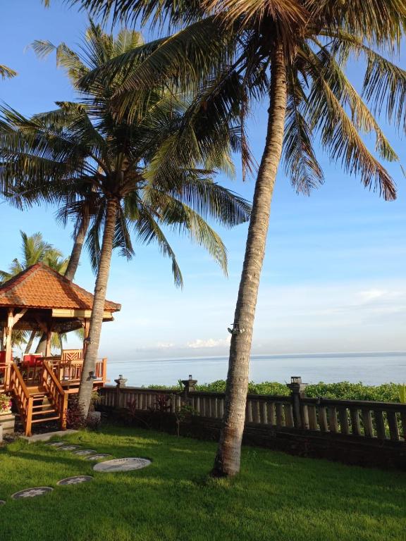two palm trees and a gazebo at Bali North Beach Villa - Ocean Front in Tianyar