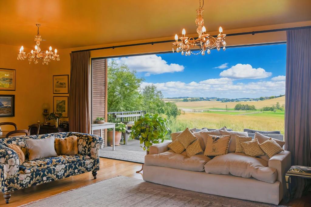 a living room with a couch and a large window at Ballymoney Cnoc in Tai Tapu