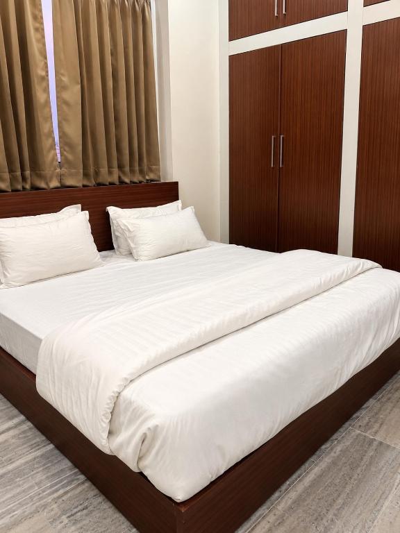a bedroom with a large bed with white sheets at Everest Guest House in Gulmarg