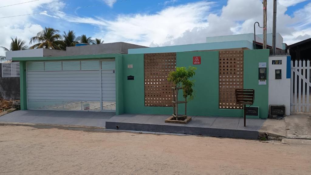 a building with two garage doors and a tree in front at Encanto à Beira-Mar com piscina no Pontal de Coruripe in Coruripe