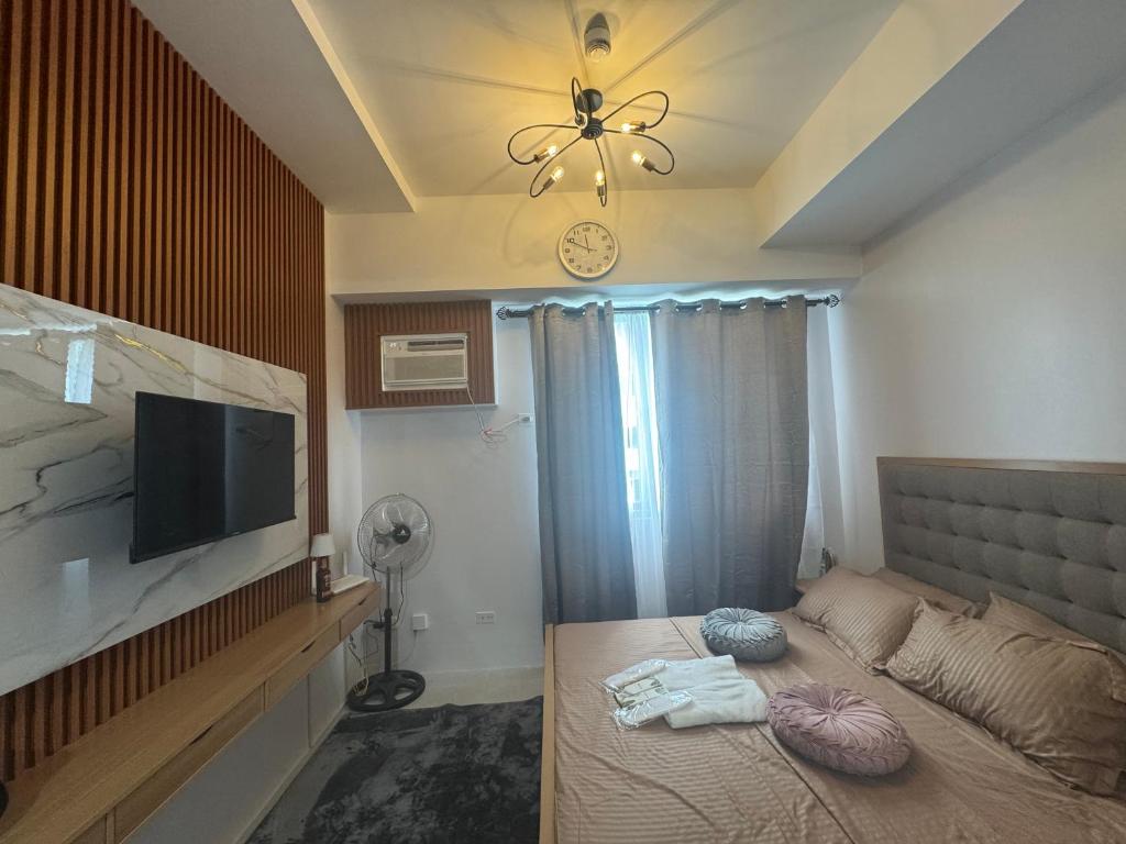 a bedroom with a bed and a flat screen tv at Staycation Hub in Mandaue City