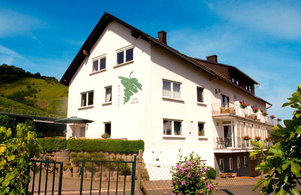 ein weißes Haus mit einem Zaun davor in der Unterkunft Weingut-Brennerei-Gästehaus Emil Dauns in Reil