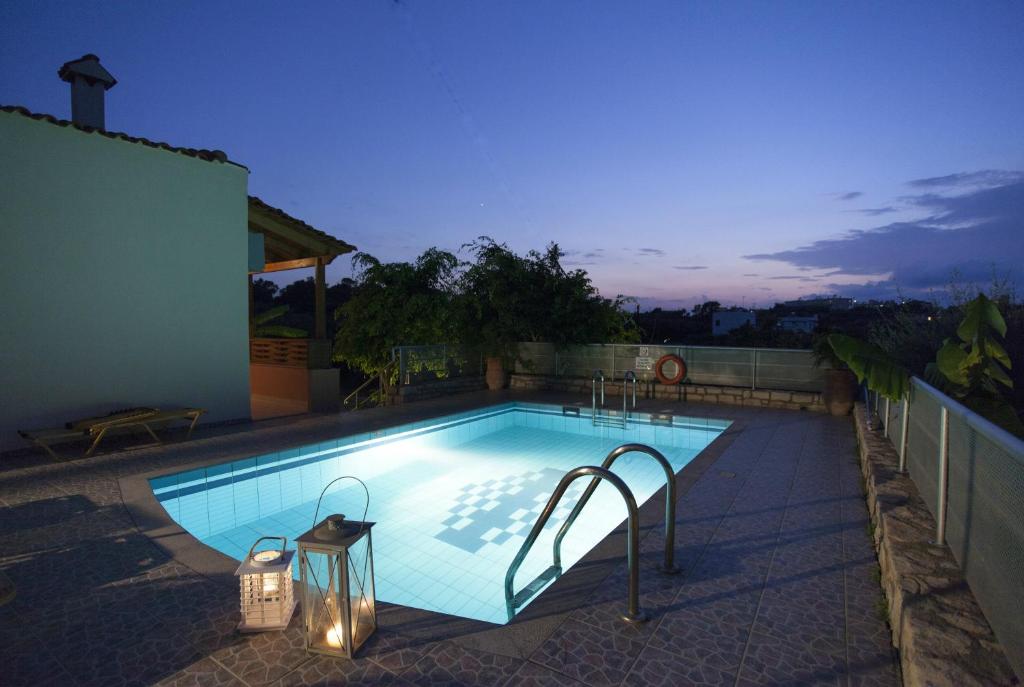 a swimming pool with lights on the side of a house at Elena-Pelagia Villas in Prínos