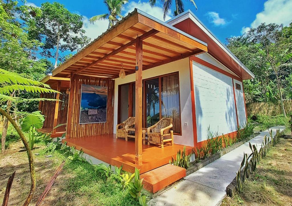 a small house with a wooden porch in a forest at Rinjani Vibe Bungalows in Tetebatu