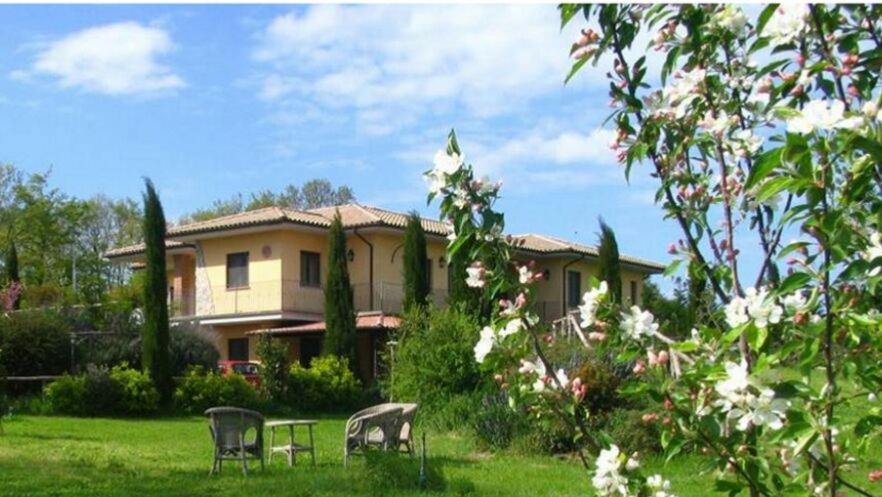 ein Haus mit drei Stühlen im Hof in der Unterkunft Agriturismo Parco delle Querce in Valentano