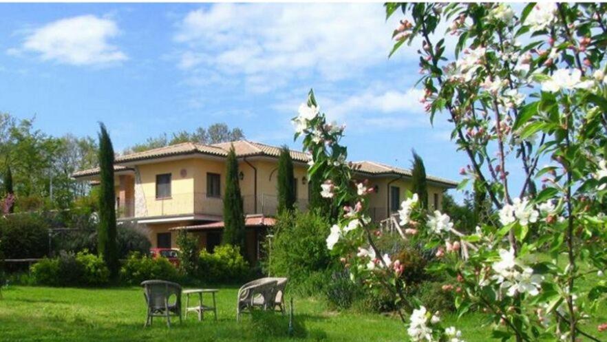 dom z trzema krzesłami na dziedzińcu w obiekcie Agriturismo Parco delle Querce w mieście Valentano