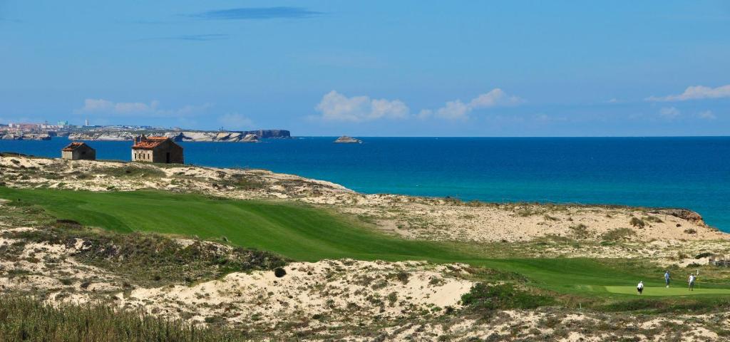 um campo de golfe no topo de uma colina arenosa com o oceano em Praia Del Rey ByThe Pools em Praia del Rei