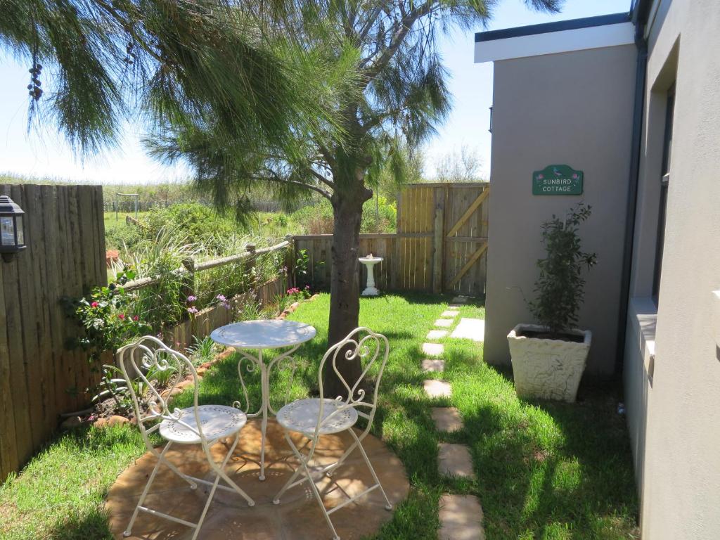 a table and chairs in a yard with a tree at Sunbird Cottage in Noordhoek