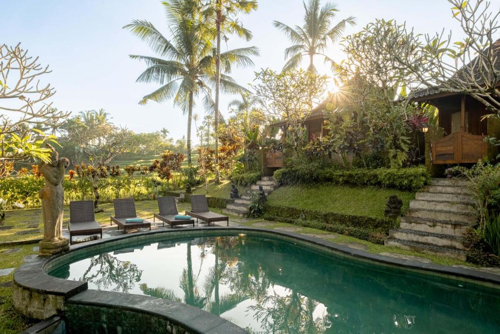 a villa with a swimming pool and palm trees at KERAMAN SUITE UBUD in Ubud