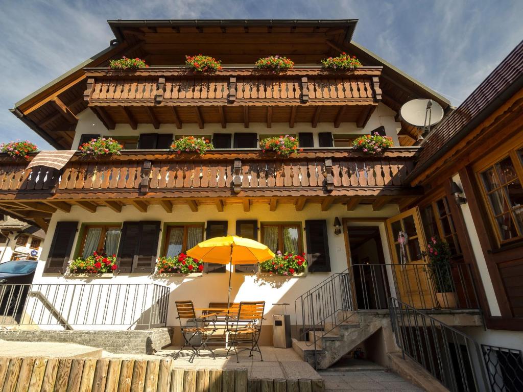 a house with a yellow umbrella and chairs in front of it at Landhotel und Apartments Sonneck in Feldberg