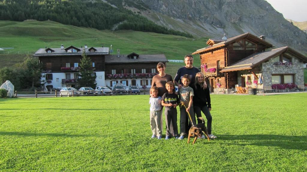 una famiglia che posa per una foto in un campo con un cane di Chalet Del Sole per gruppi a Livigno