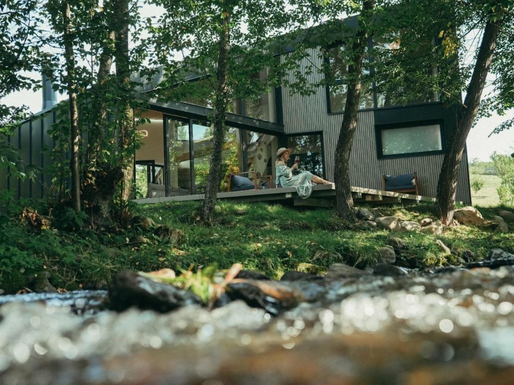 a woman sitting on a bench in front of a house at Chalets Szőcs-birtok in Izvoare