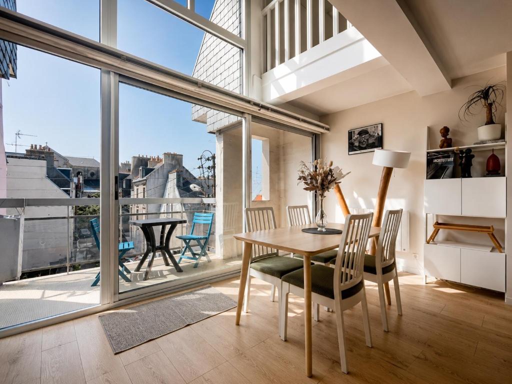 a dining room with a table and chairs and a large window at Appartement moderne baigné de lumière en centre-ville in Douarnenez