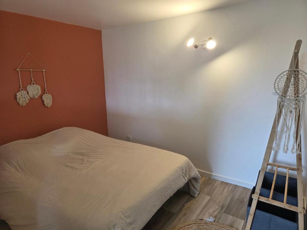 a bedroom with a white bed and a ladder at Petite maison sympathique in Auvers