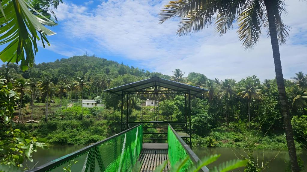 a bridge over a river in a forest with a building at Adan Paradise Riverview Homestay in Attappādi