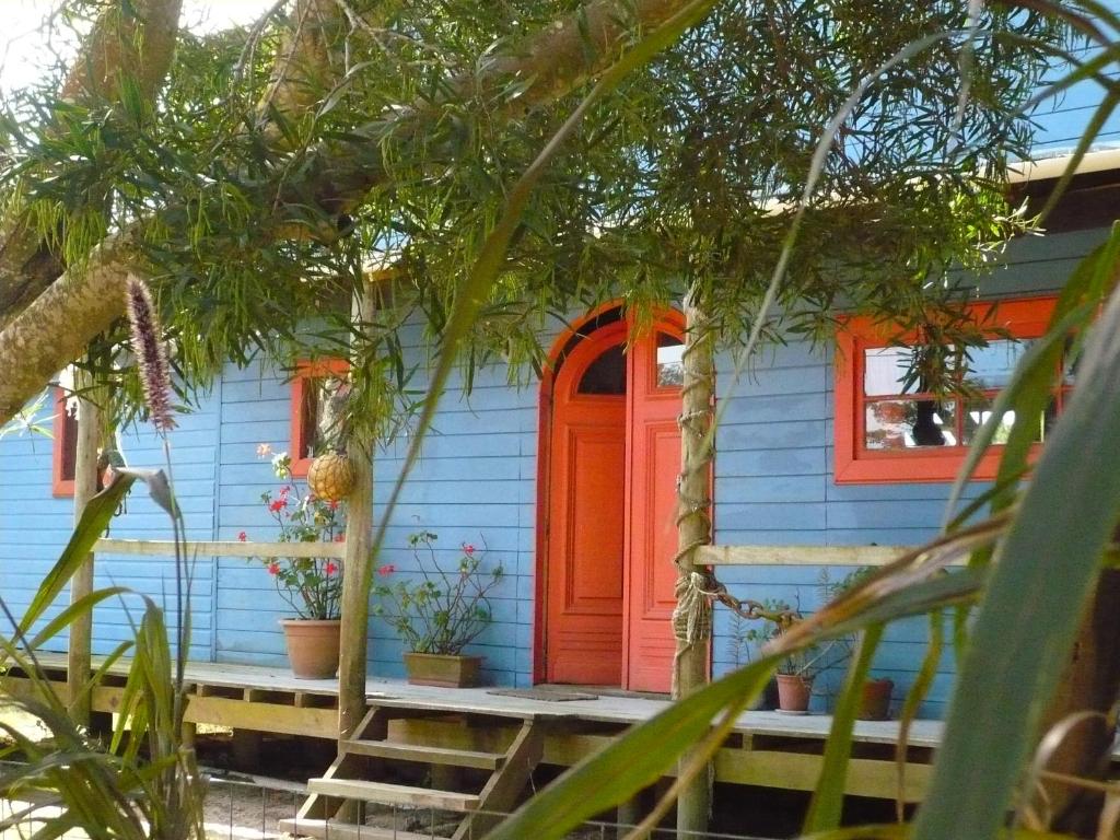 una casa azul con una puerta naranja y ventanas en Casa La Juanita, en José Ignacio