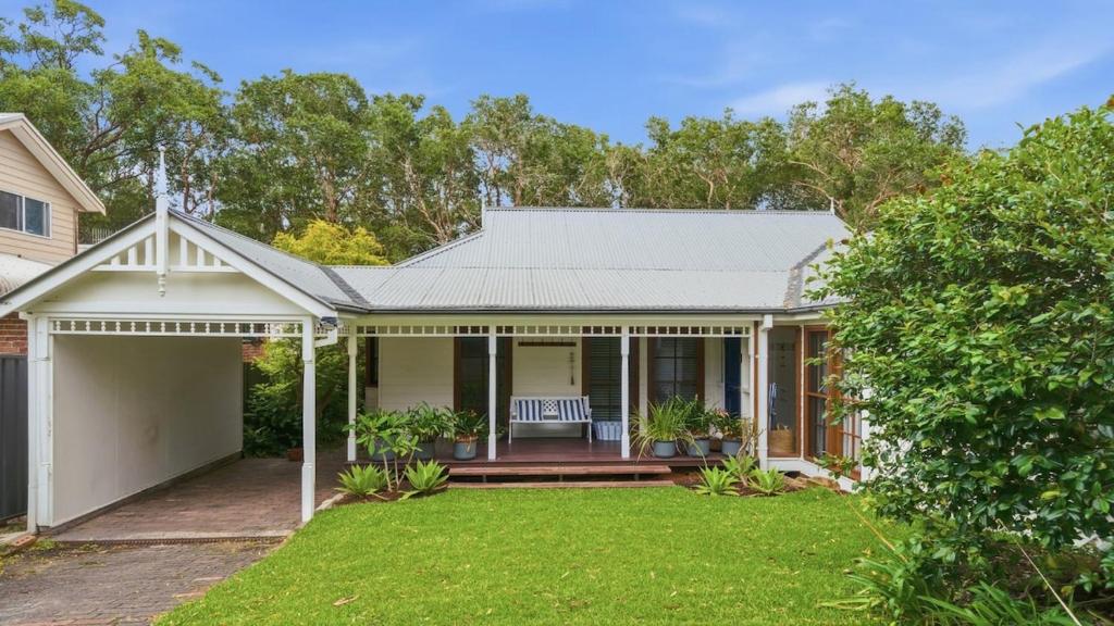 a house with a porch with a lawn at Forries Beach Cottage in Wamberal