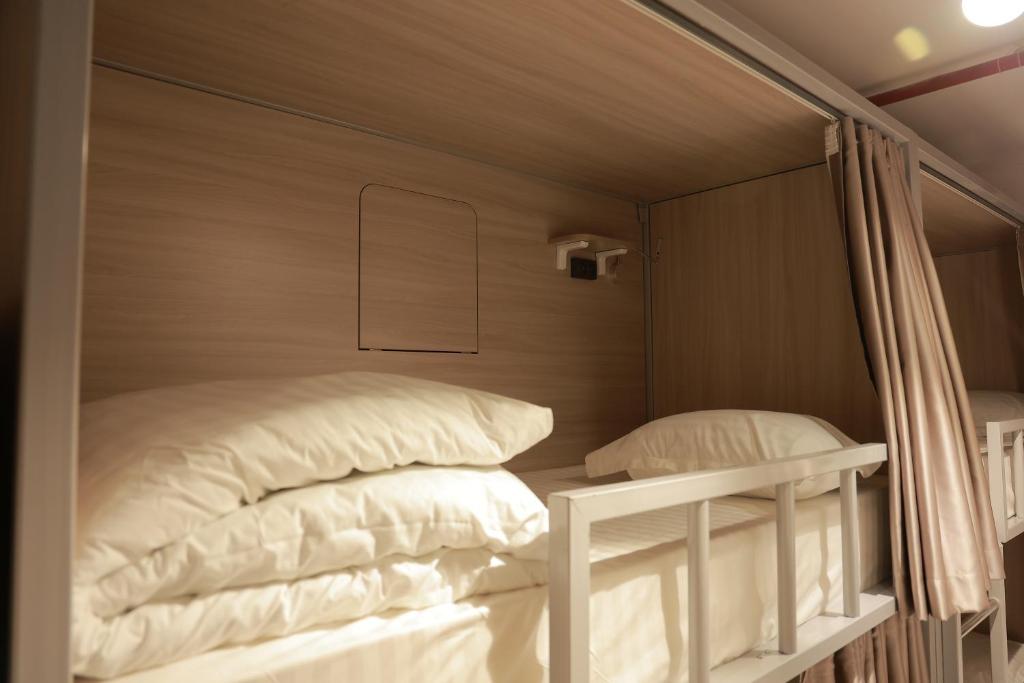 a bed with white pillows in a room at PREMIUM DOO Hostel in Tashkent