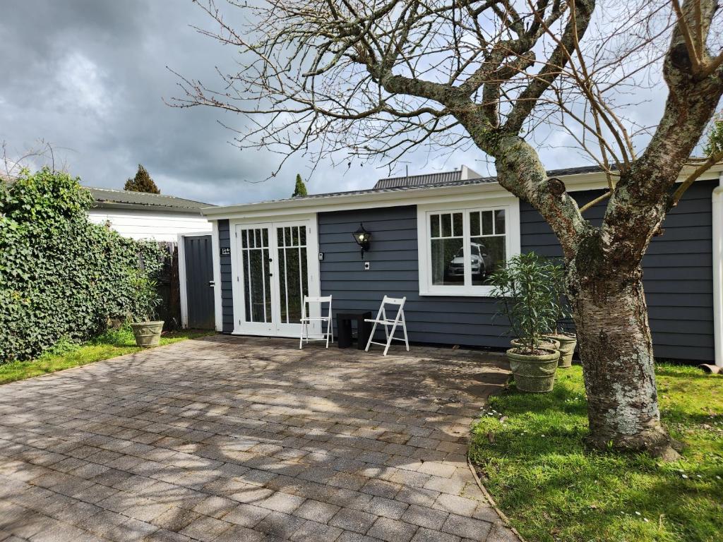 a blue house with a tree in the yard at Little Eden in Matamata
