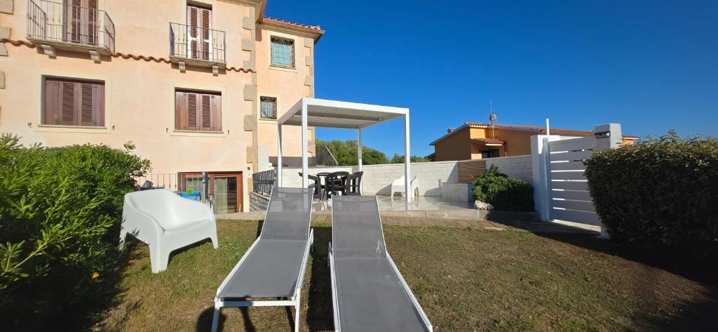 a house with a bench and a white chair in a yard at La casa al mare, Pittulongu in Olbia