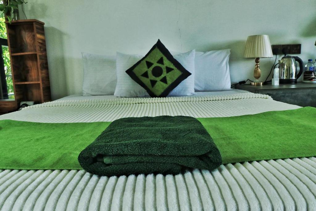 a large bed with a green blanket on it at farm house chalet in Dambulla