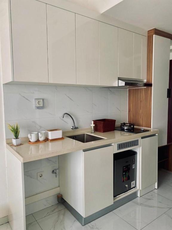 a kitchen with white cabinets and a sink and a stove at Sky House Hotel Style Bed IKEA 5min in Kampungklapa 2