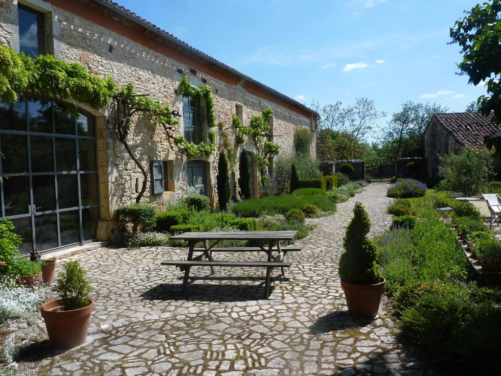 une terrasse en pierre avec une table de pique-nique en face d'un bâtiment dans l'établissement LA CLE d'ESCAMPS, à Escamps