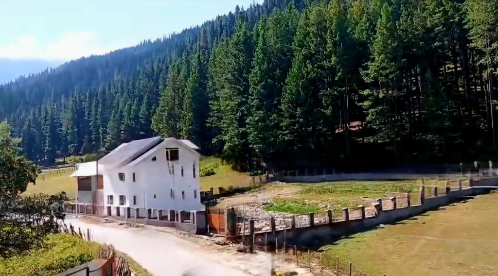 a train traveling past a white building next to a river at Samoon Guest House in Karnāl