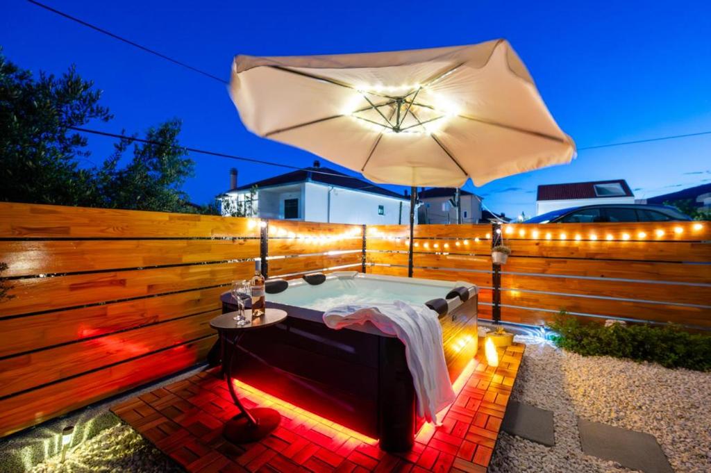 a hot tub with an umbrella and lights at Ante room's in Trogir