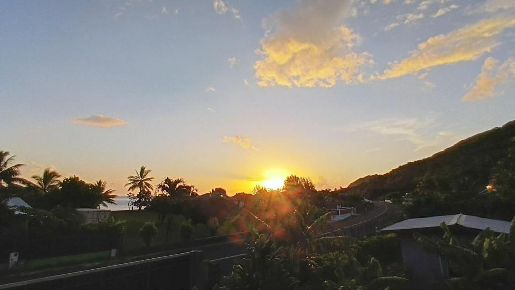 a sunset over a road with the sun in the sky at Chalet Familiale Vue Mer et Coucher de Soleil Moorea in Moorea